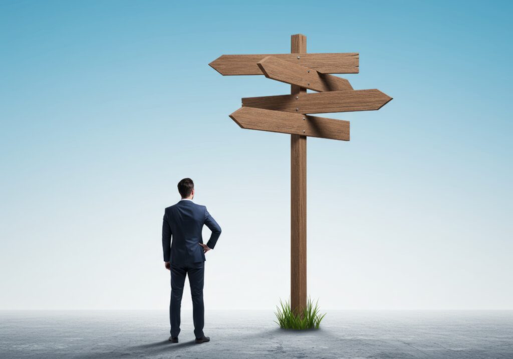 A businessman stands before a signpost with multiple paths, symbolizing difficult decisions Perfect for illustrating business choices and uncertainty.