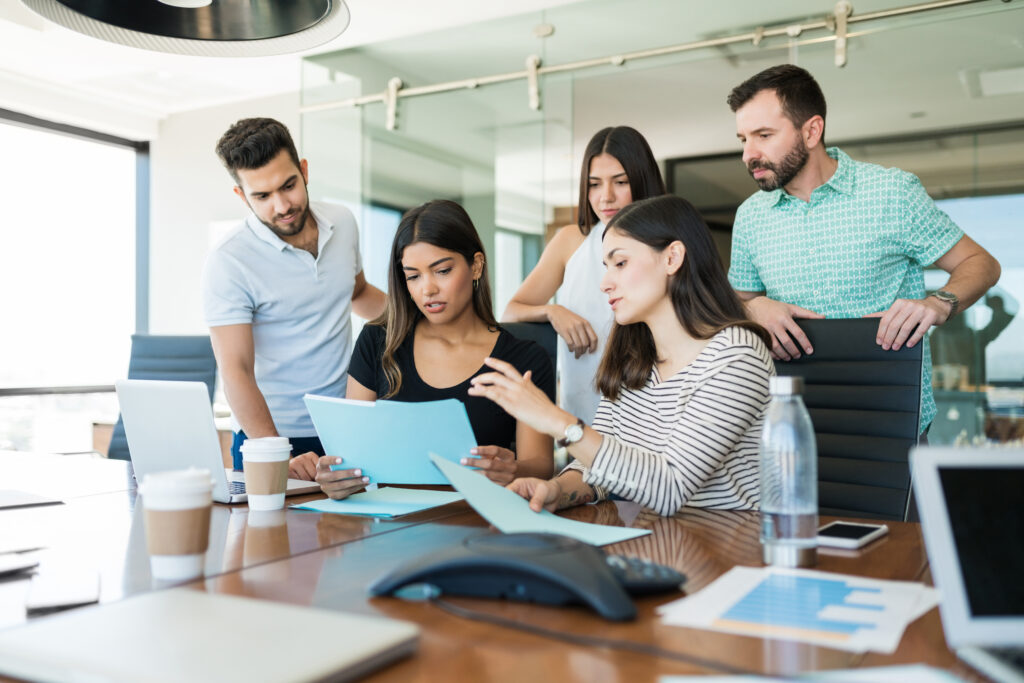 Team of business professionals discussing over file at desk in creative office during meeting