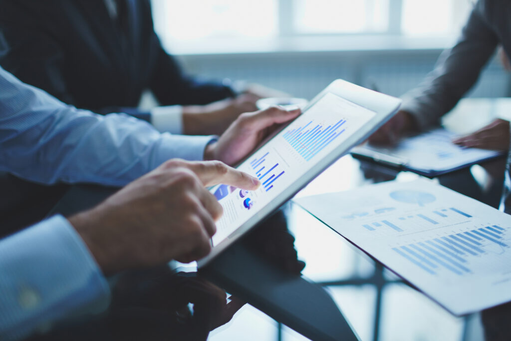 Image of businessperson pointing at a report on a touchpad at a meeting